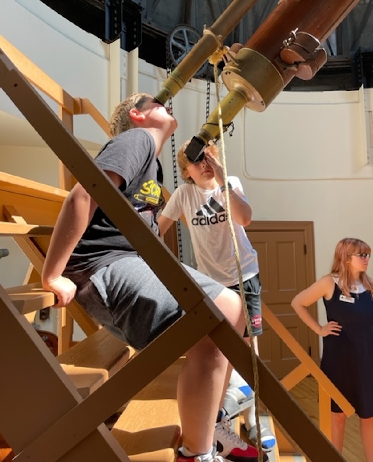Students exploring a historic telescope